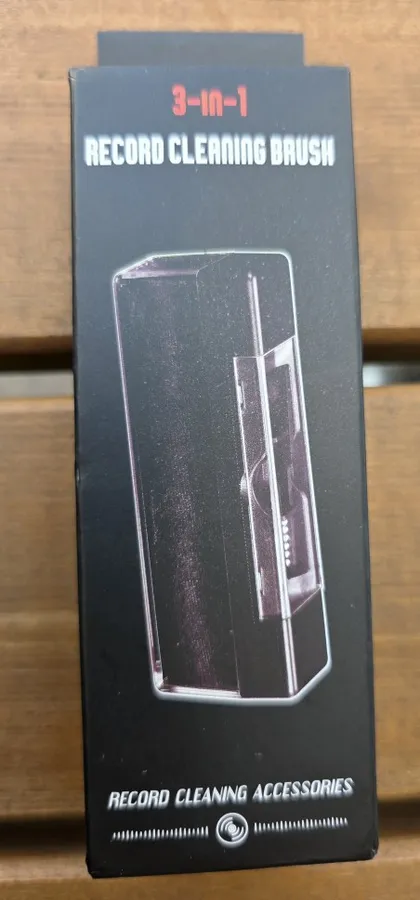 Black retail box printed 3-in-1 Record Cleaning Brush, photographed on a wooden slat surface