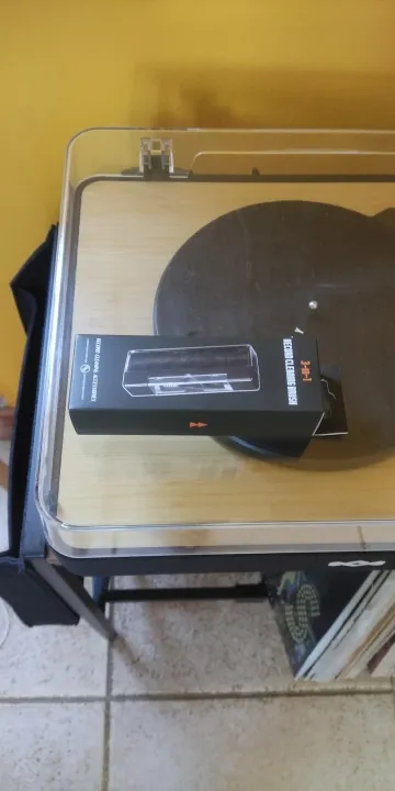 Unopened Tonebrush box resting on a turntable platter, with records stored on the shelf underneath